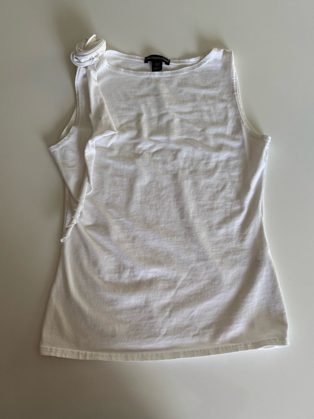 White tank top with a rose detail on the shoulder